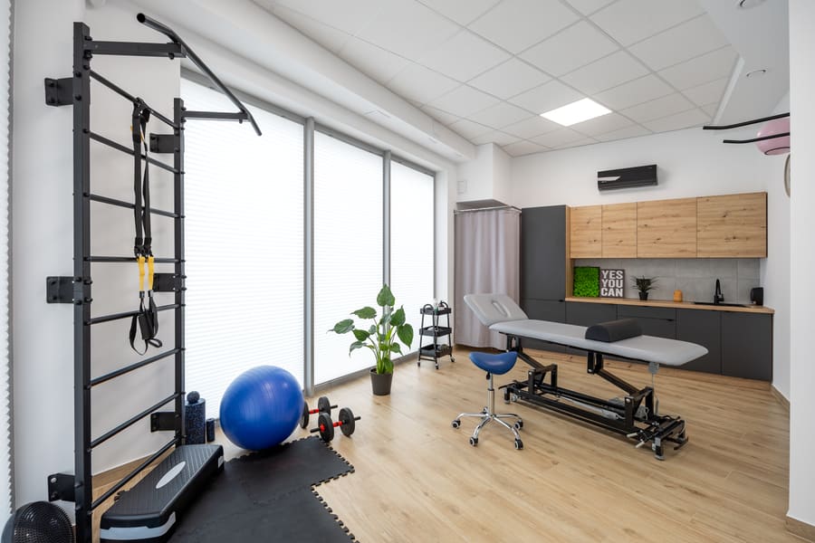 Sala terapeutyczna z leżanką, drabinką gimnastyczną i sprzętem do ćwiczeń